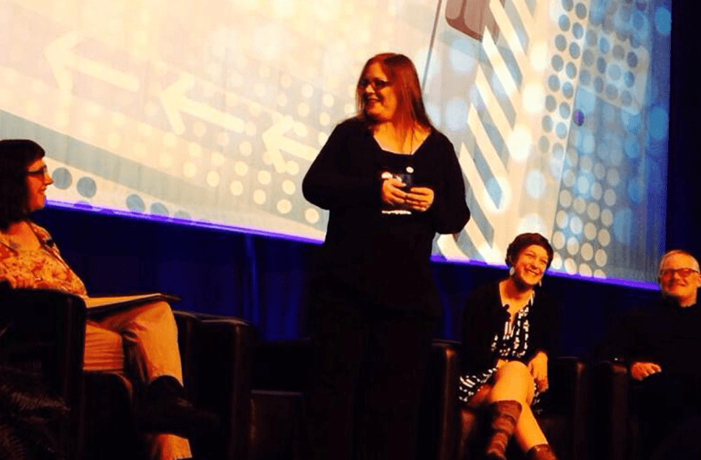 Cindy Leonard speaking on a stage with three other people